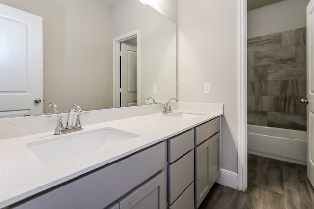 bathroom with hardwood / wood-style floors, vanity, and tiled shower / bath