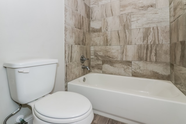 bathroom with hardwood / wood-style floors, toilet, and tiled shower / bath