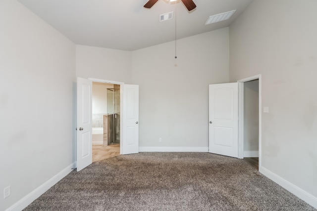 unfurnished bedroom with carpet, ceiling fan, a high ceiling, and ensuite bath