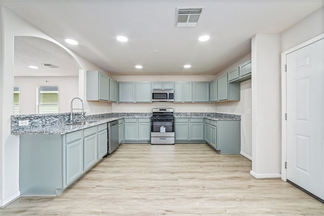 kitchen featuring light stone counters, a sink, visible vents, light wood-style floors, and appliances with stainless steel finishes