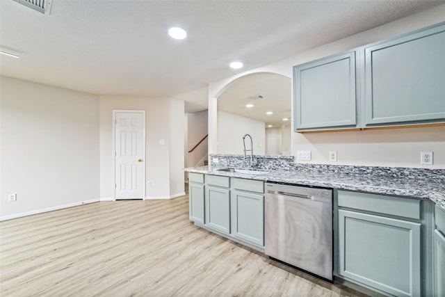 kitchen with light stone counters, visible vents, stainless steel dishwasher, light wood-style floors, and a sink