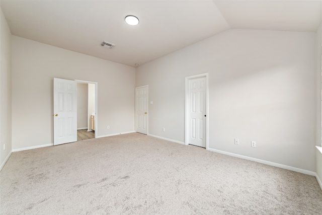 carpeted empty room with vaulted ceiling, visible vents, and baseboards