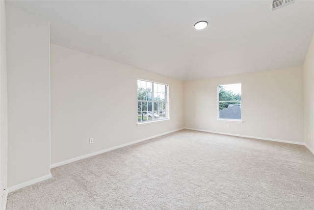 empty room featuring baseboards, visible vents, vaulted ceiling, and carpet flooring