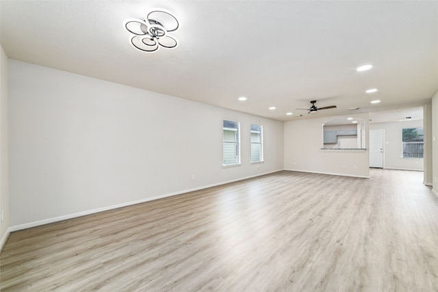 unfurnished living room with baseboards, a ceiling fan, and light wood-style floors