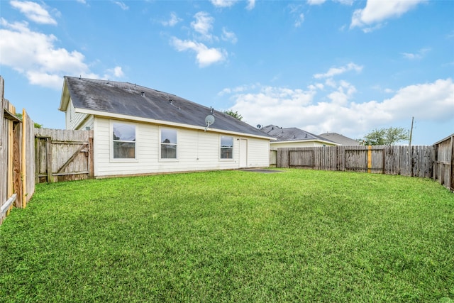 back of property with a fenced backyard and a yard