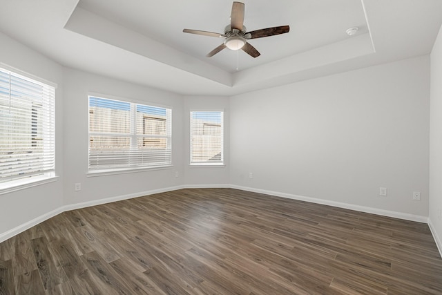 spare room featuring a tray ceiling, dark wood-type flooring, and ceiling fan