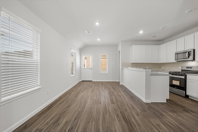 kitchen with dark wood-type flooring, stainless steel appliances, tasteful backsplash, and white cabinets