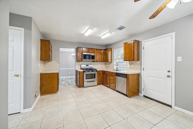 kitchen featuring sink, light tile patterned floors, a textured ceiling, and appliances with stainless steel finishes