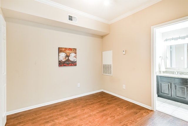 spare room with sink, wood-type flooring, and ornamental molding