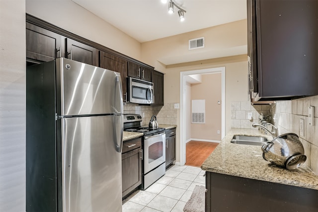 kitchen with sink, tasteful backsplash, light tile patterned flooring, light stone counters, and stainless steel appliances