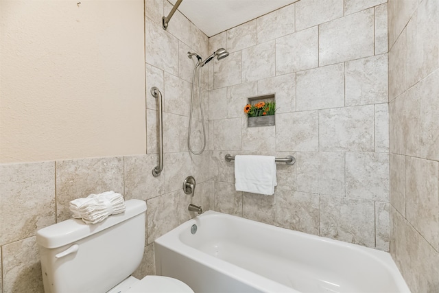 bathroom featuring tiled shower / bath combo, tile walls, and toilet