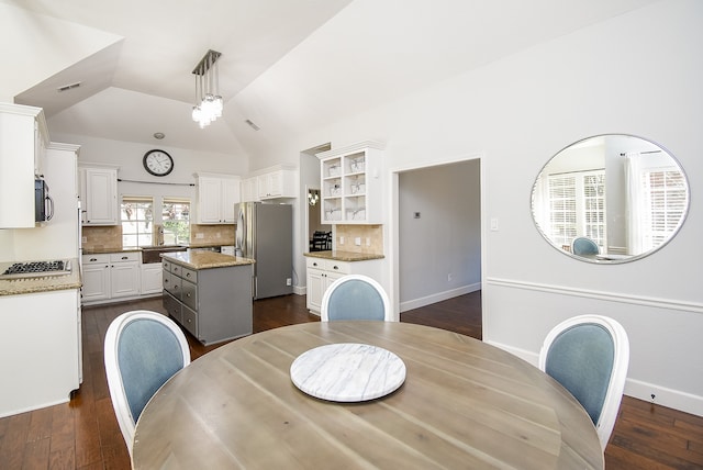 dining space with dark hardwood / wood-style floors, vaulted ceiling, and sink