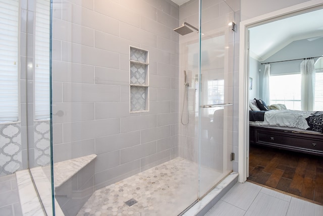 bathroom with hardwood / wood-style flooring, lofted ceiling, and a shower with door