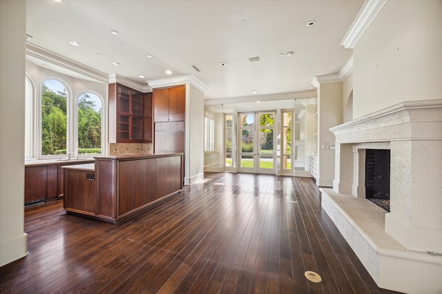 kitchen featuring a fireplace, a kitchen island, ornamental molding, and dark wood-type flooring