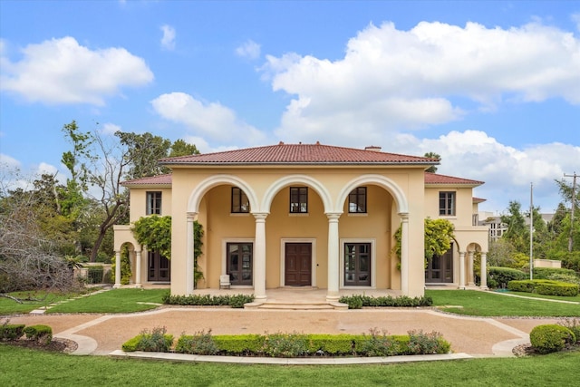 view of front of property with a front yard, a tiled roof, and stucco siding