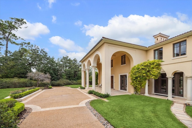 view of front of house with a patio area, a front lawn, and stucco siding