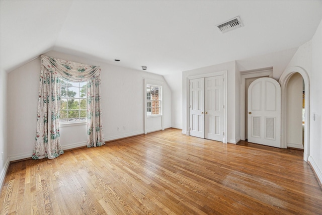 unfurnished bedroom with lofted ceiling, baseboards, visible vents, and wood finished floors