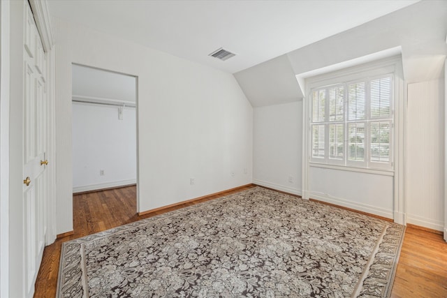 additional living space with hardwood / wood-style floors and vaulted ceiling