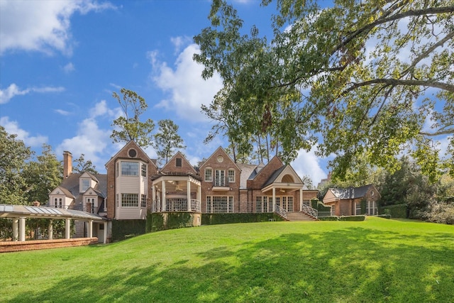 rear view of property with a ceiling fan and a yard