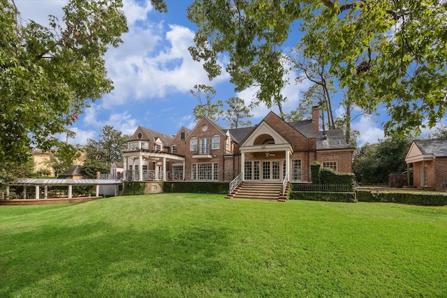 back of house featuring french doors, brick siding, a yard, and a pergola