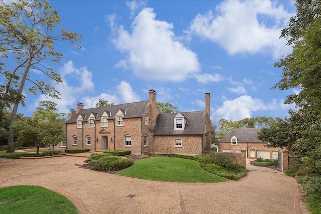 view of front of house with a front yard, brick siding, and a chimney