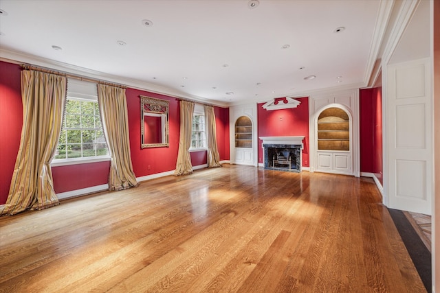 unfurnished living room featuring hardwood / wood-style flooring, built in features, and ornamental molding