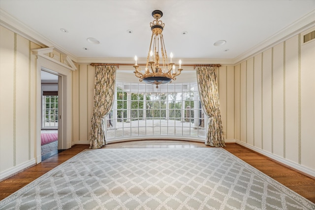 unfurnished room featuring a chandelier, hardwood / wood-style flooring, and ornamental molding