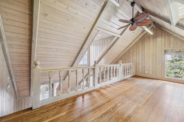 bonus room with lofted ceiling with beams, wood walls, ceiling fan, wooden ceiling, and hardwood / wood-style floors