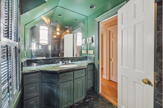 bathroom featuring a shower with door and vanity