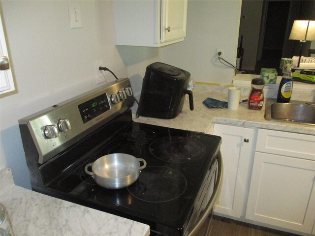 kitchen featuring electric range, dark hardwood / wood-style floors, and white cabinets