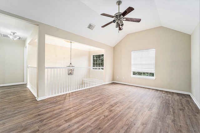 spare room featuring ceiling fan with notable chandelier, dark hardwood / wood-style flooring, and vaulted ceiling