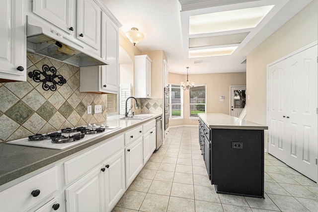 kitchen with white cabinetry, a center island, sink, white gas stovetop, and decorative backsplash