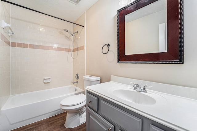 full bathroom featuring vanity, a textured ceiling, wood-type flooring, toilet, and tiled shower / bath