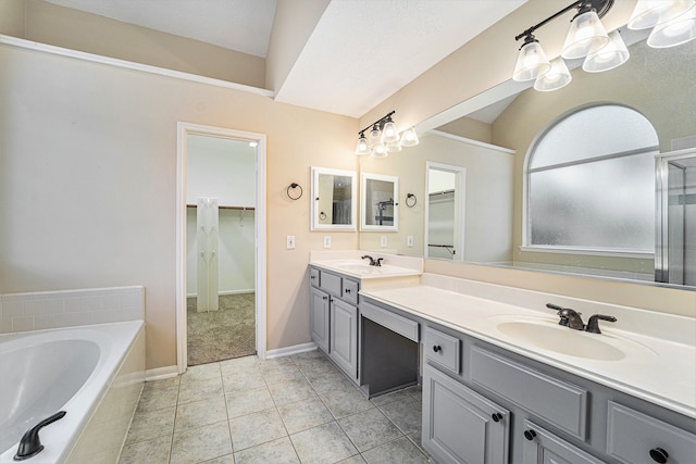 bathroom with a washtub, a textured ceiling, vanity, and tile patterned flooring