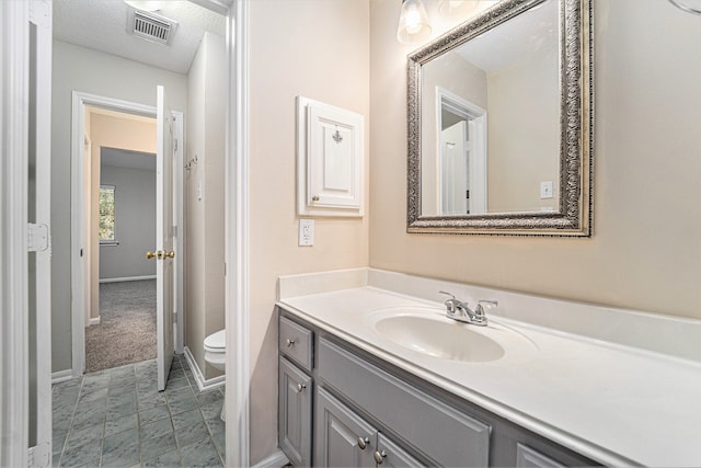 bathroom with vanity, a textured ceiling, and toilet