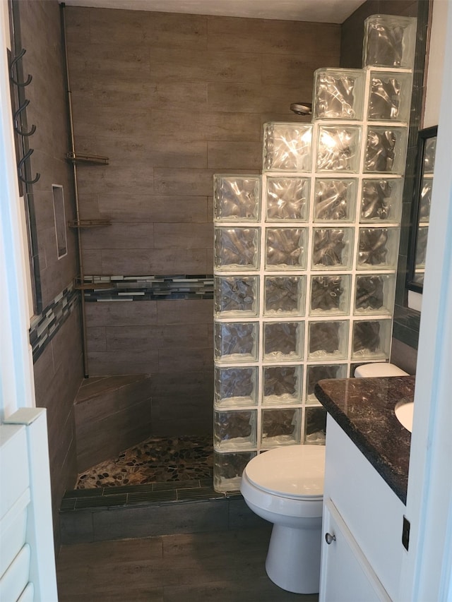 bathroom with tiled shower, vanity, hardwood / wood-style flooring, and toilet