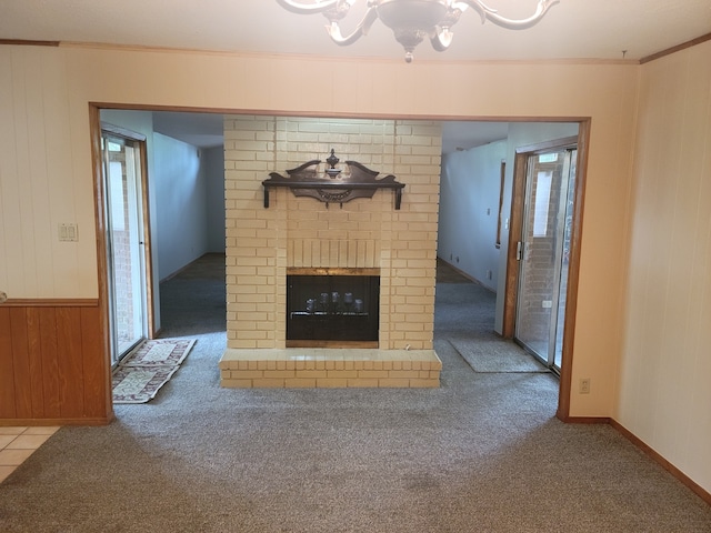 unfurnished living room with wood walls, plenty of natural light, carpet floors, and a chandelier