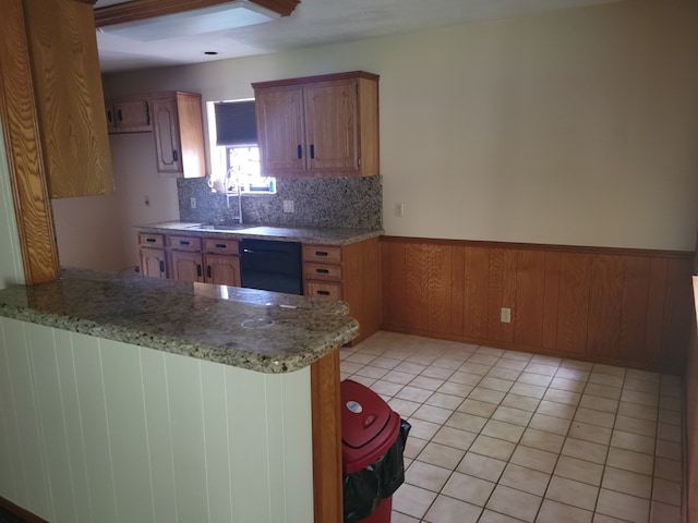 kitchen featuring black dishwasher, wooden walls, kitchen peninsula, decorative backsplash, and light tile patterned flooring