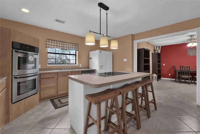 kitchen featuring a kitchen bar, appliances with stainless steel finishes, sink, a center island, and hanging light fixtures