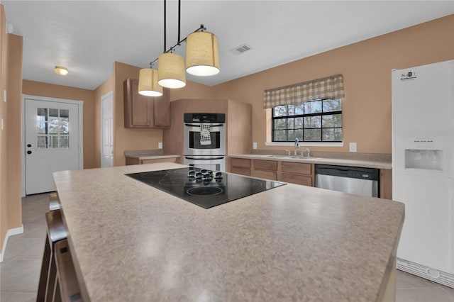 kitchen featuring stainless steel appliances, sink, light tile patterned floors, a center island, and hanging light fixtures