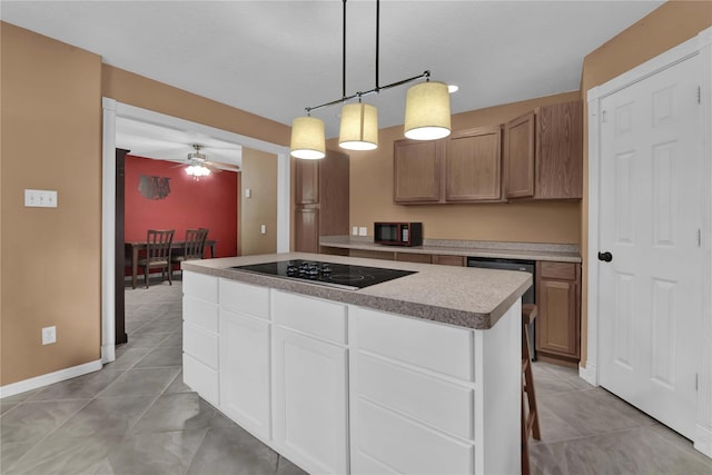 kitchen featuring a center island, black electric stovetop, ceiling fan, decorative light fixtures, and white cabinetry