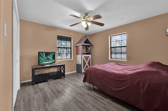 bedroom with multiple windows, ceiling fan, a textured ceiling, and hardwood / wood-style flooring