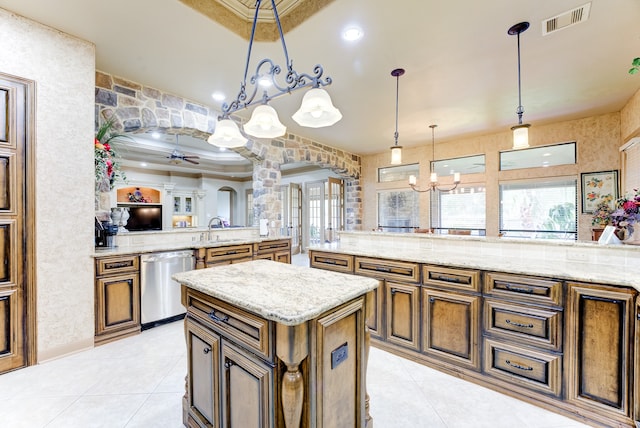 kitchen with stainless steel dishwasher, light stone counters, ceiling fan with notable chandelier, decorative light fixtures, and a center island