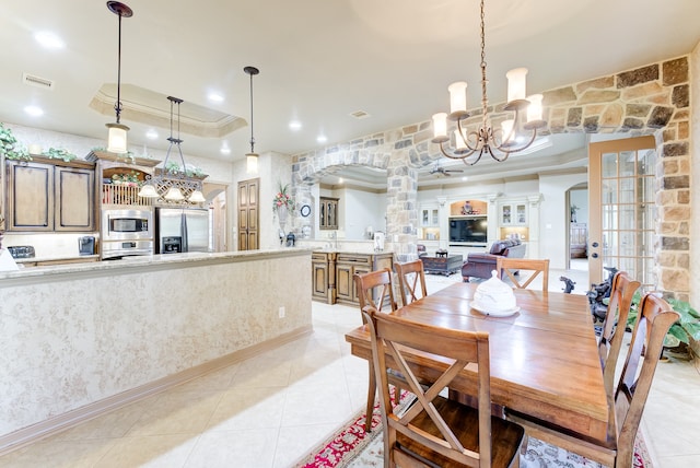 tiled dining space with a raised ceiling, crown molding, and a notable chandelier