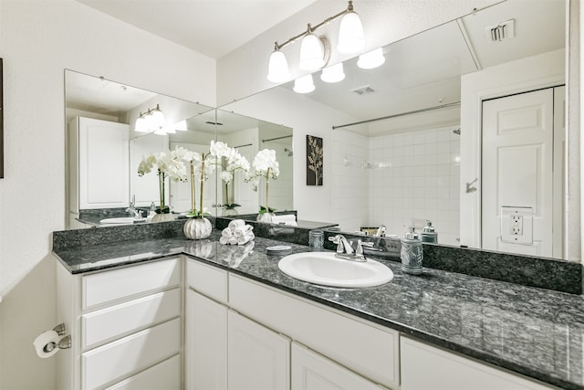 bathroom featuring tiled shower and vanity