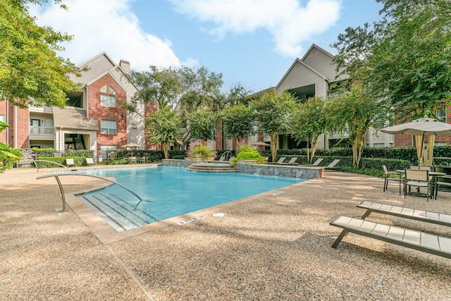 view of swimming pool featuring pool water feature and a patio