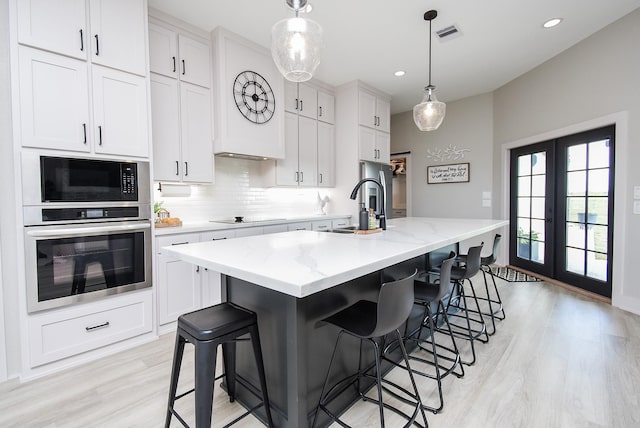 15007 Barak Rd Unit P, Guy, TX 77444 - kitchen with black appliances, light wood-type flooring, decorative backsplash, a sink, and white cabinetry