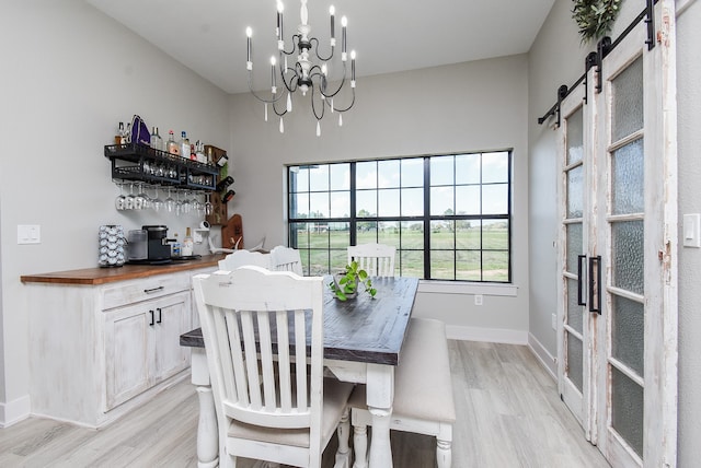 dining room featuring a barn door, light hardwood / wood-style floors, and an inviting chandelier