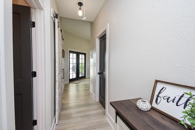 hall featuring lofted ceiling, light hardwood / wood-style flooring, and french doors