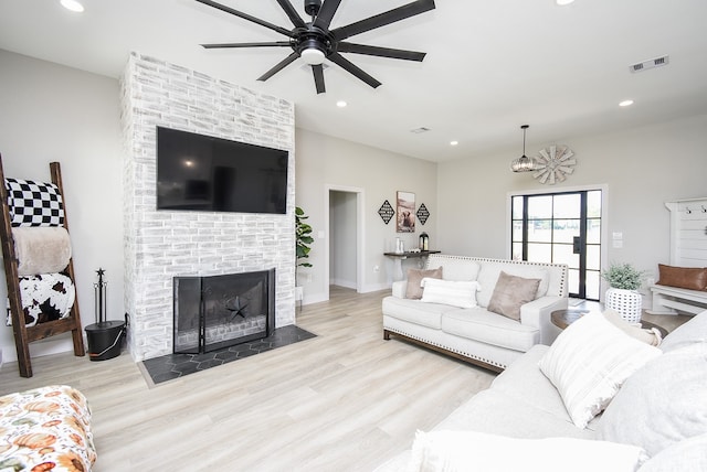 living room with ceiling fan, a fireplace, and light wood-type flooring